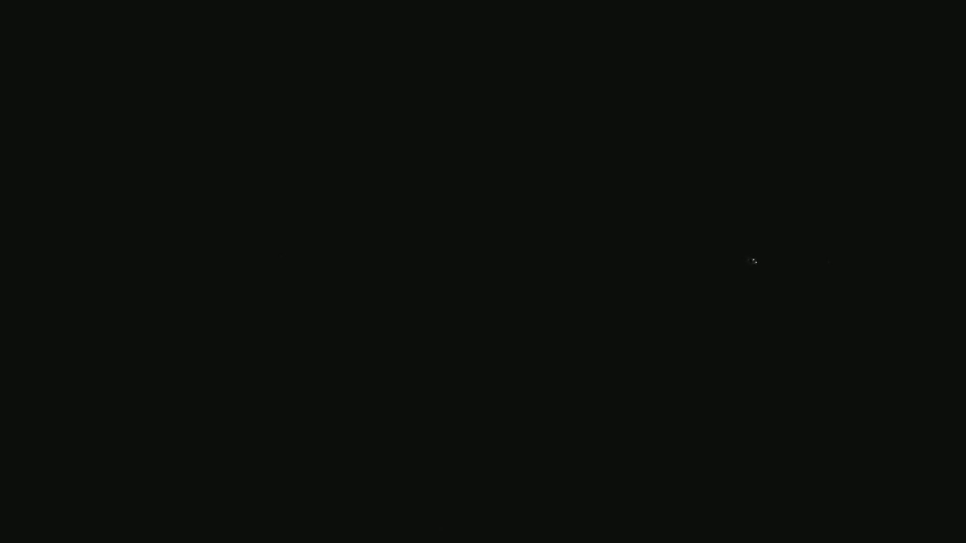 The image shows a completely black background with a single, faint, bright speck of light near the center.