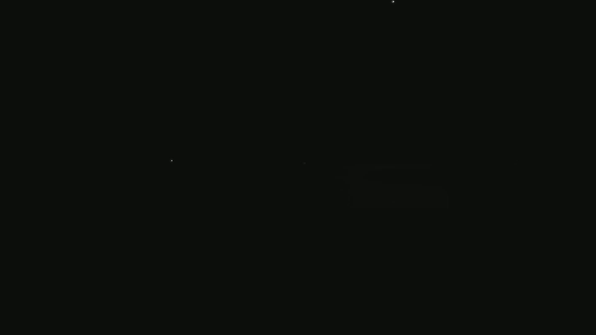 A dark, nighttime scene shows a few faint lights in the distance.