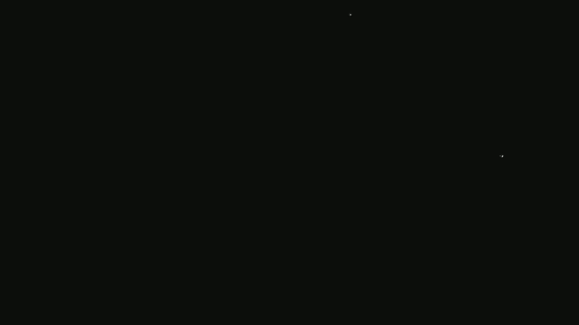 The image is a completely black screen with a few extremely small, faint white dots.