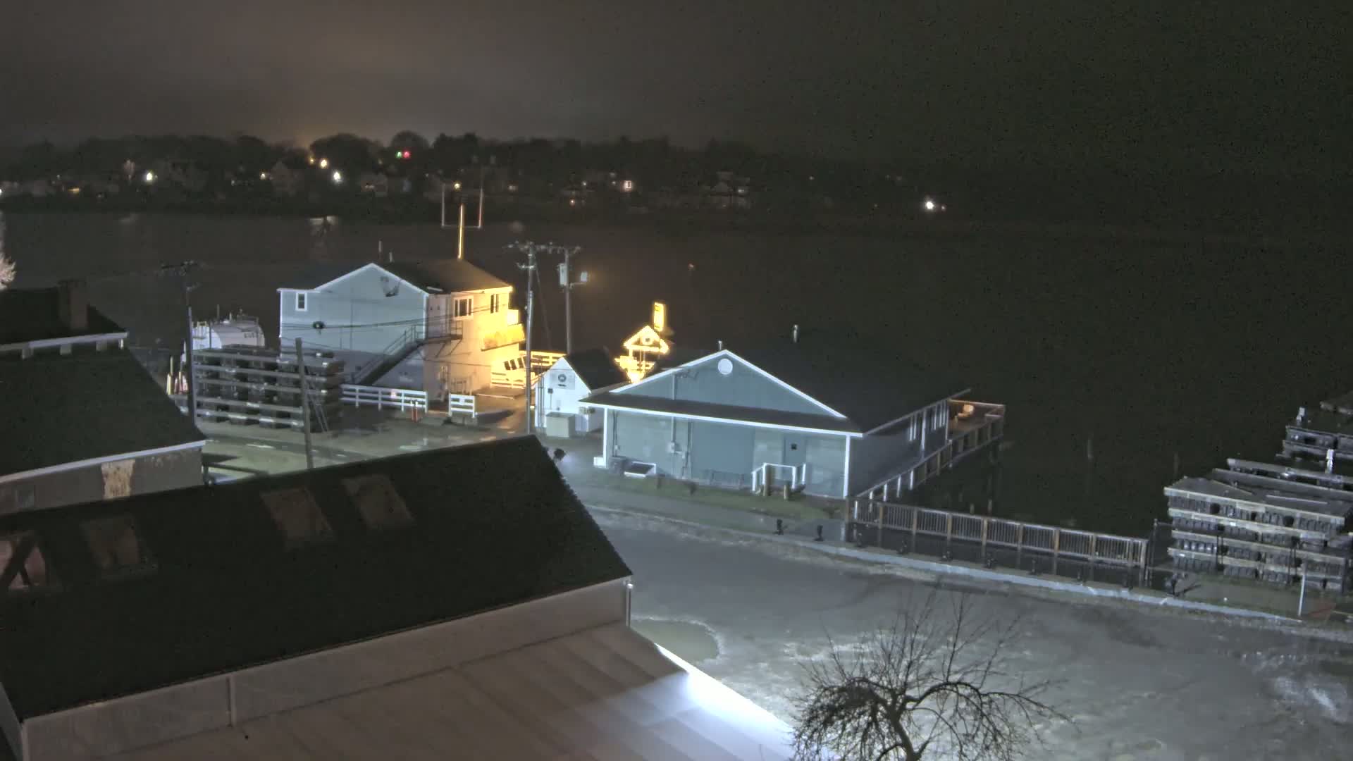 At night, floodwaters cover a street and partially submerge buildings near a body of water.