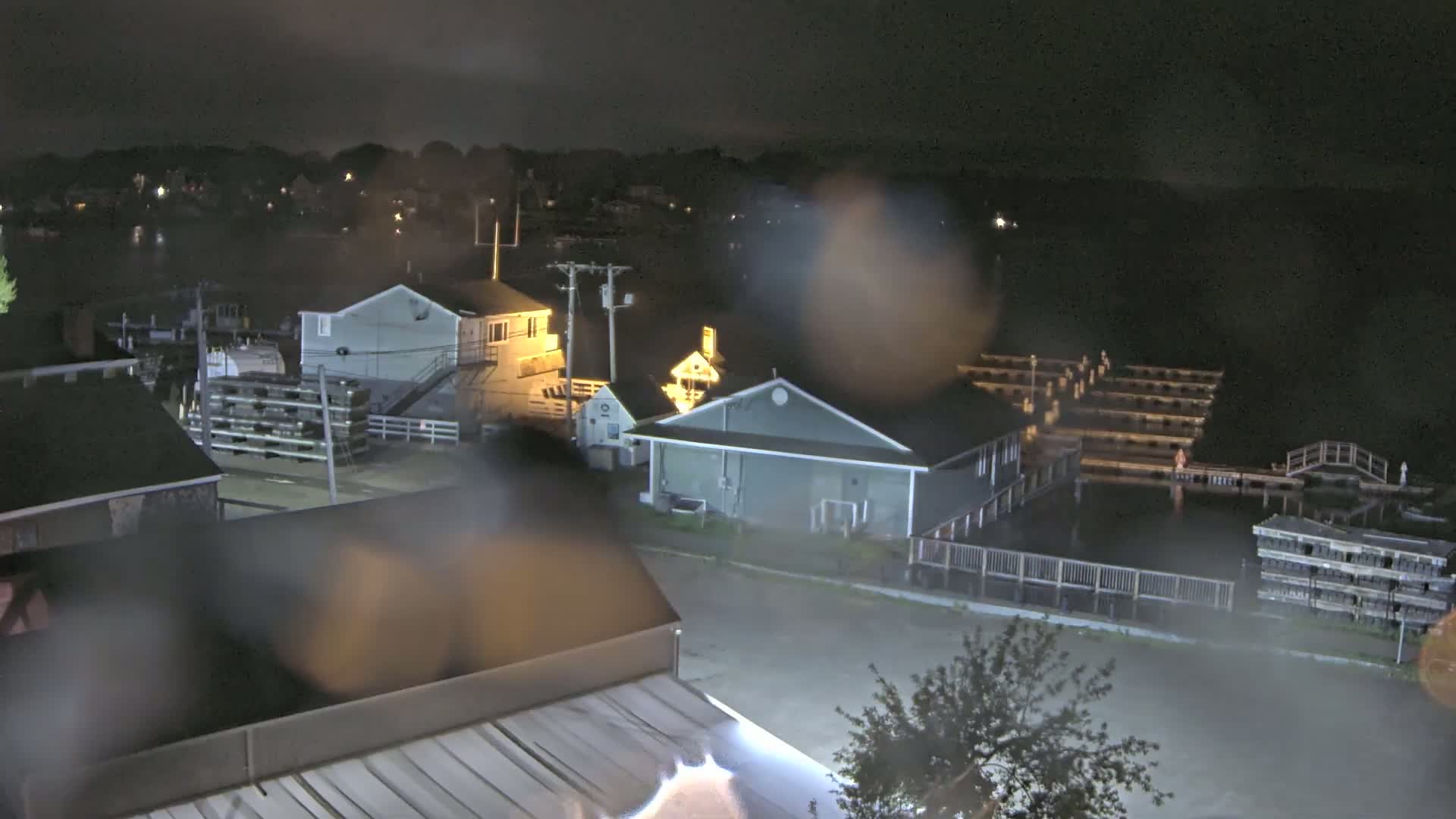 A nighttime view of a waterfront area with buildings and docks, obscured by rain.