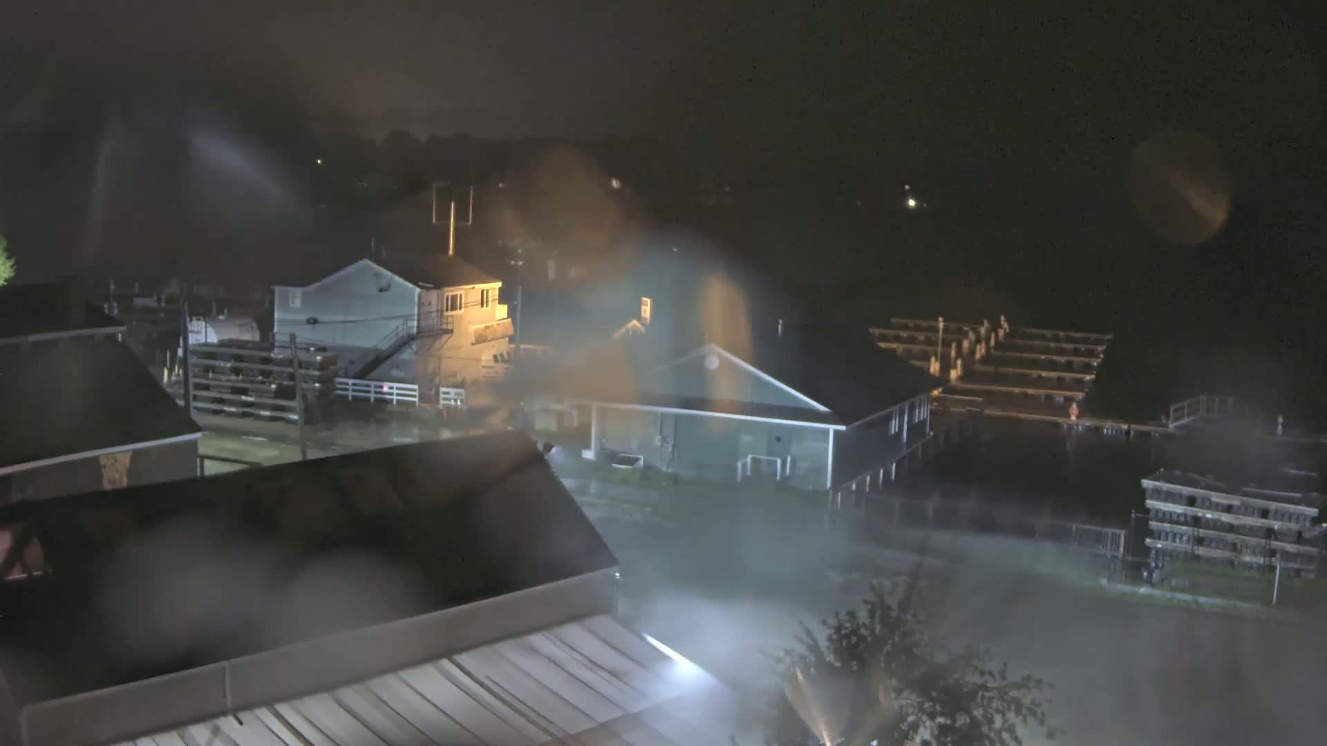 A nighttime view of houses and a marina during a heavy rain storm.