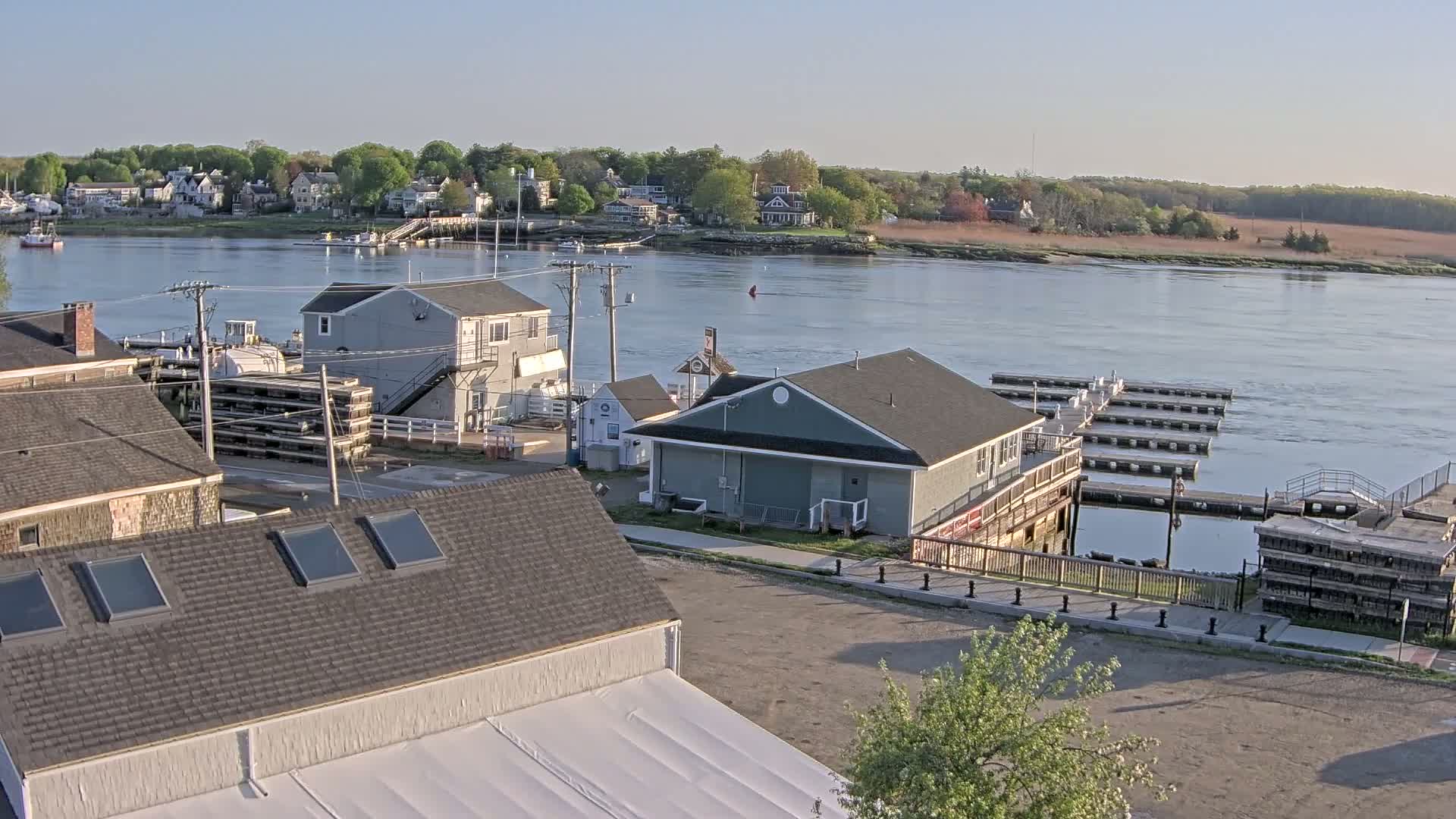 A waterfront town with several buildings, a marina, and a river under a clear sky.