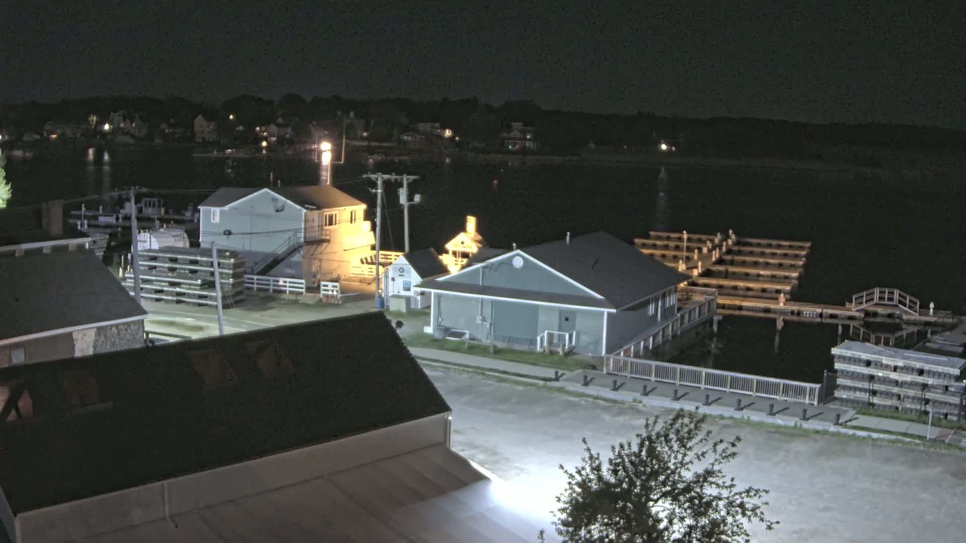 A nighttime view of a waterfront area with several buildings, docks, and a calm body of water.