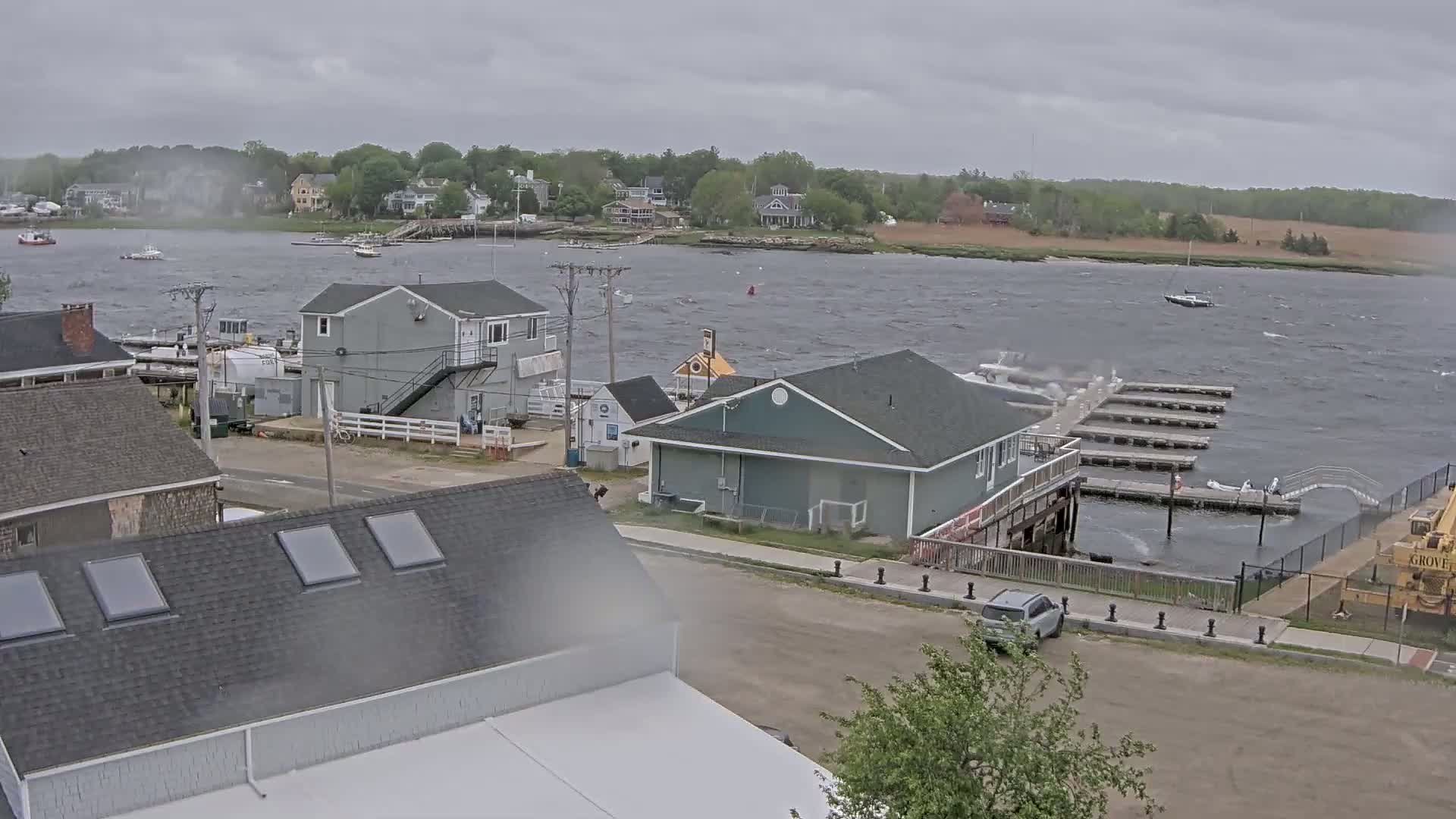 A waterfront scene with several buildings and a marina on a windy, overcast day.