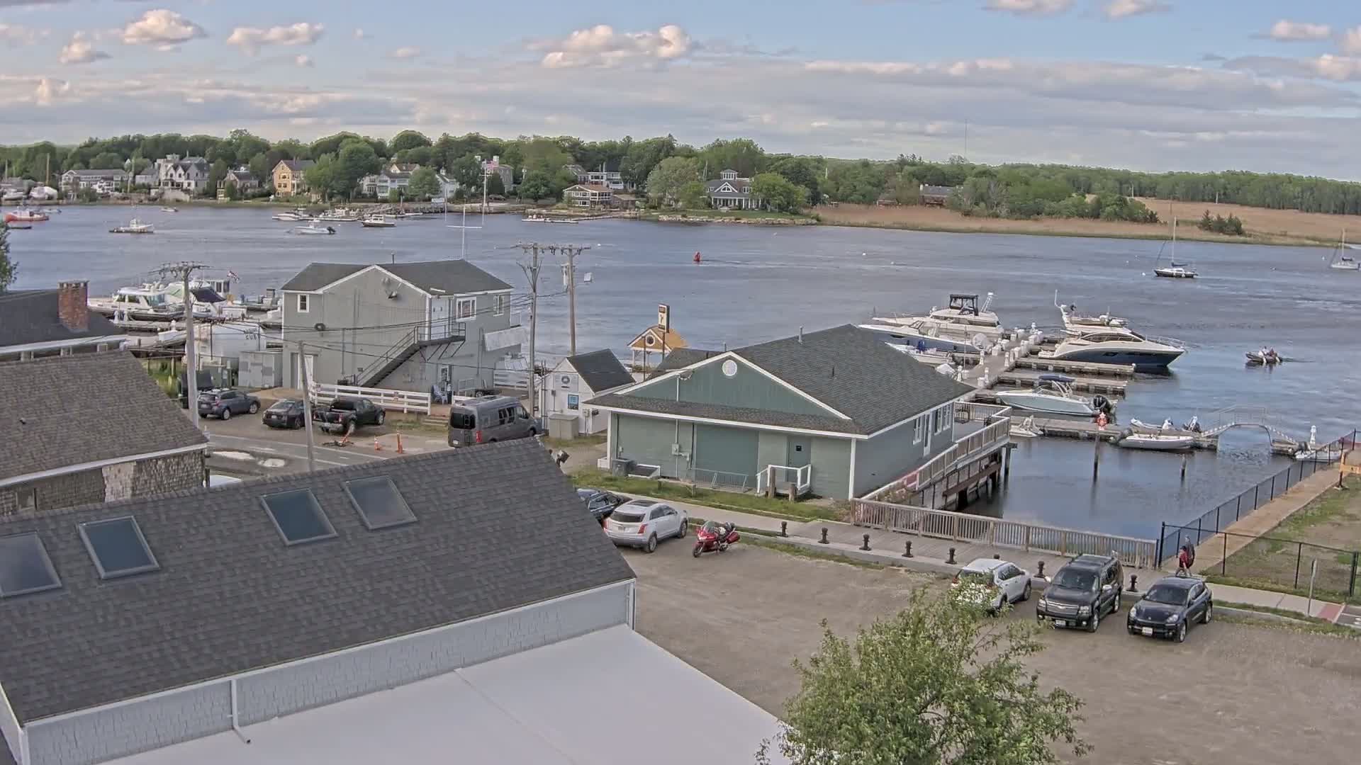 A waterfront town with docked boats under a partly cloudy sky.