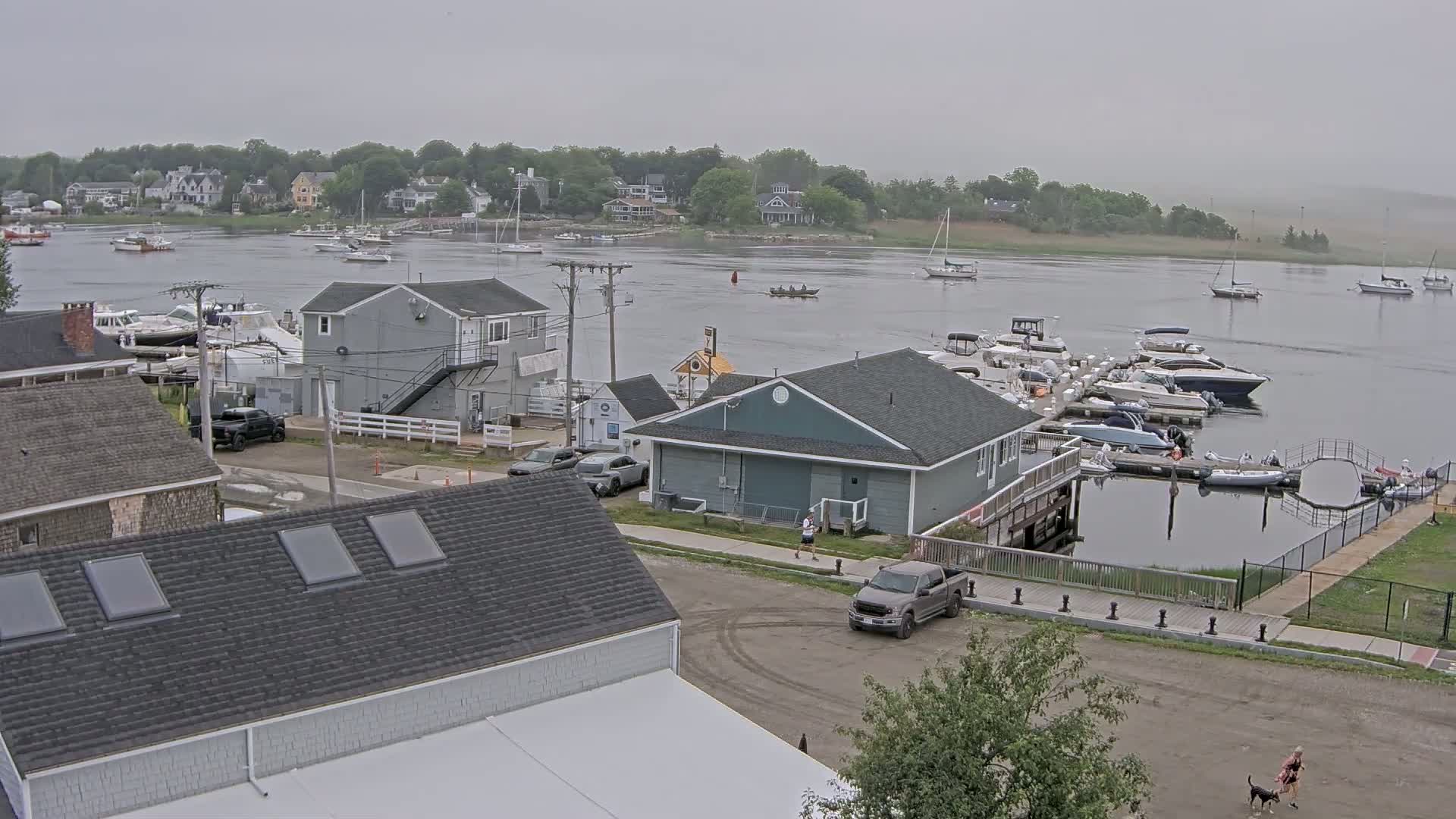 A mostly cloudy day overlooks a marina filled with boats, with houses and buildings lining the waterfront.