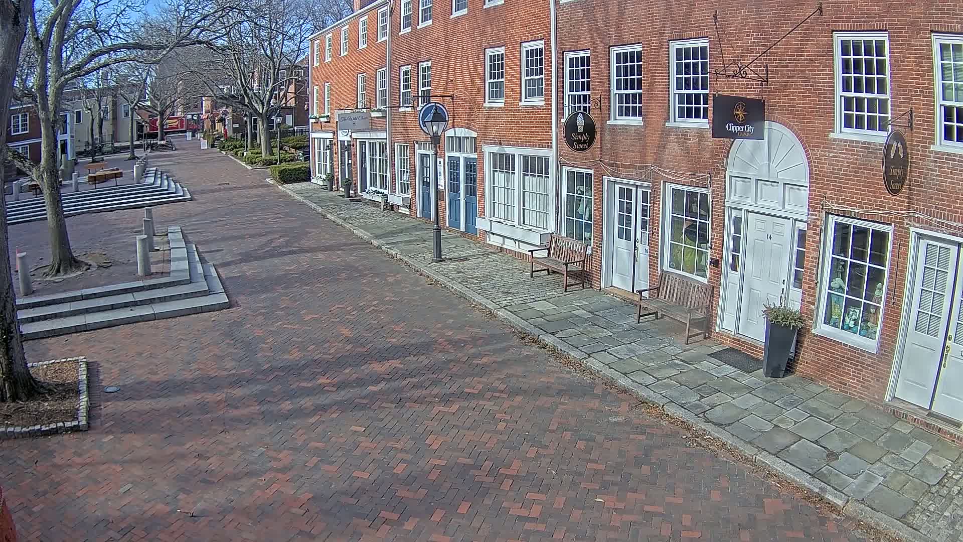 A brick street lined with brick buildings on a sunny day.