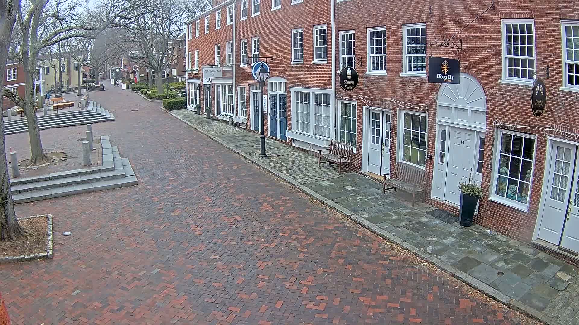 A brick street lined with brick buildings on an overcast day.