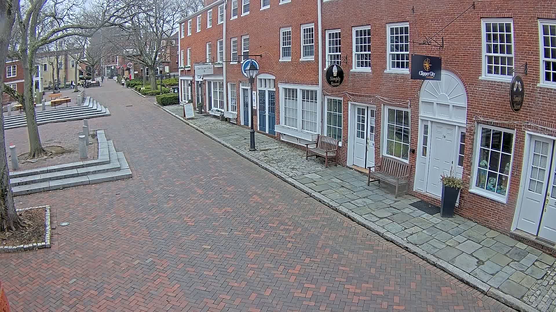 A brick-paved street lined with brick buildings on a cloudy day.
