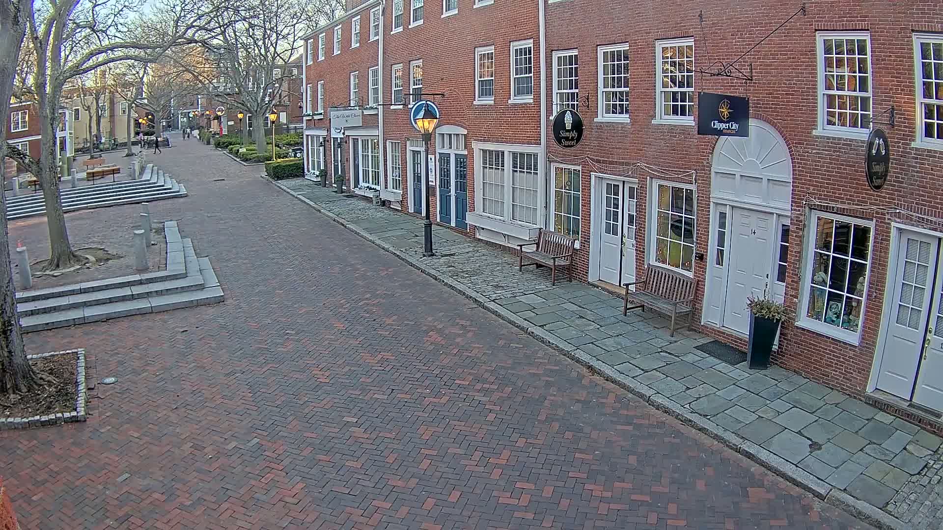 A brick street lined with brick buildings on a partly sunny day.