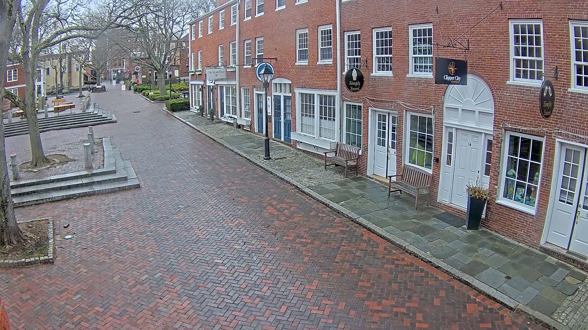 A brick street lined with brick buildings on a cloudy day.