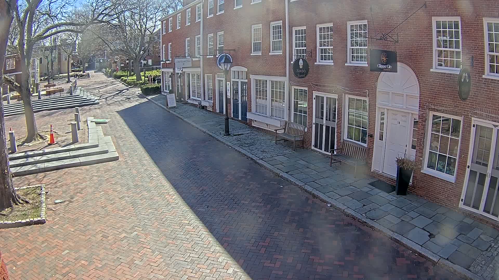 A brick street lined with brick buildings on a sunny day.