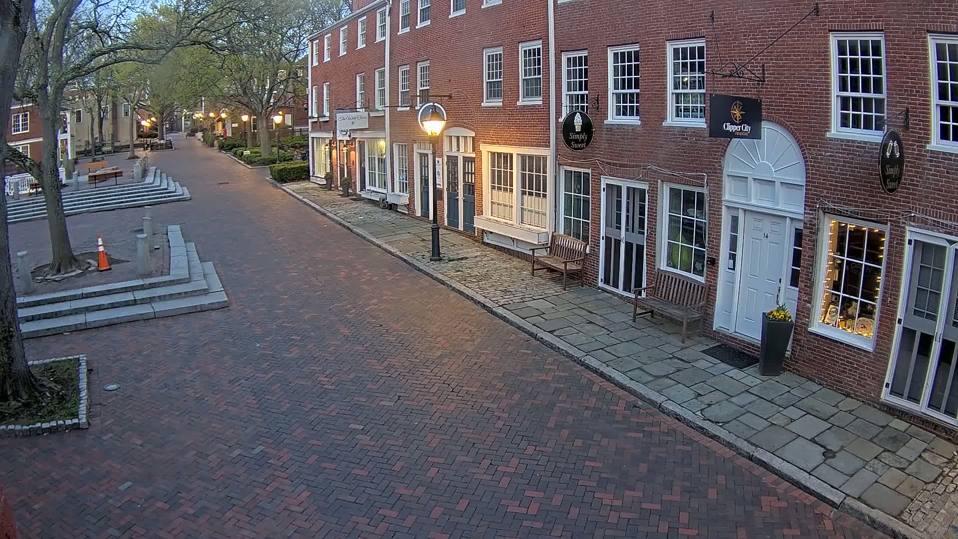 A brick-paved street lined with brick buildings under a twilight sky.