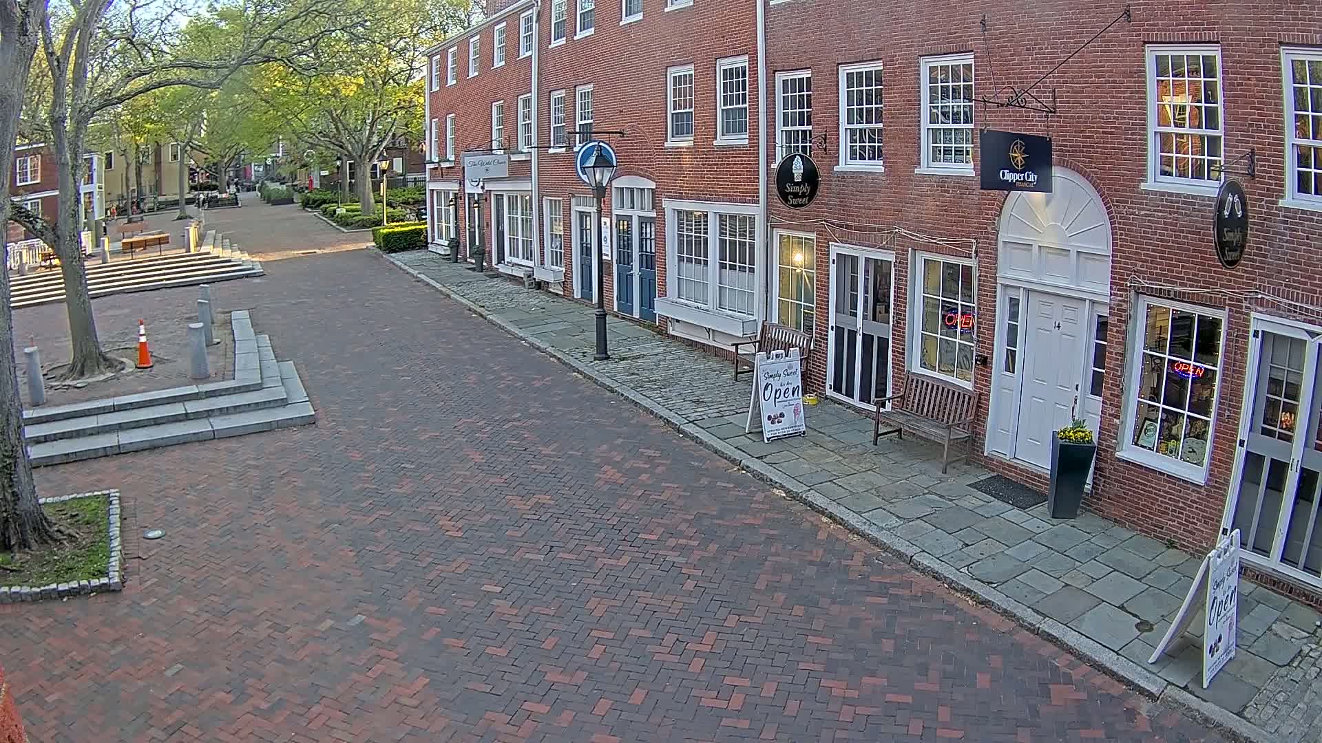 A brick-paved street lined with brick buildings under a partly sunny sky.