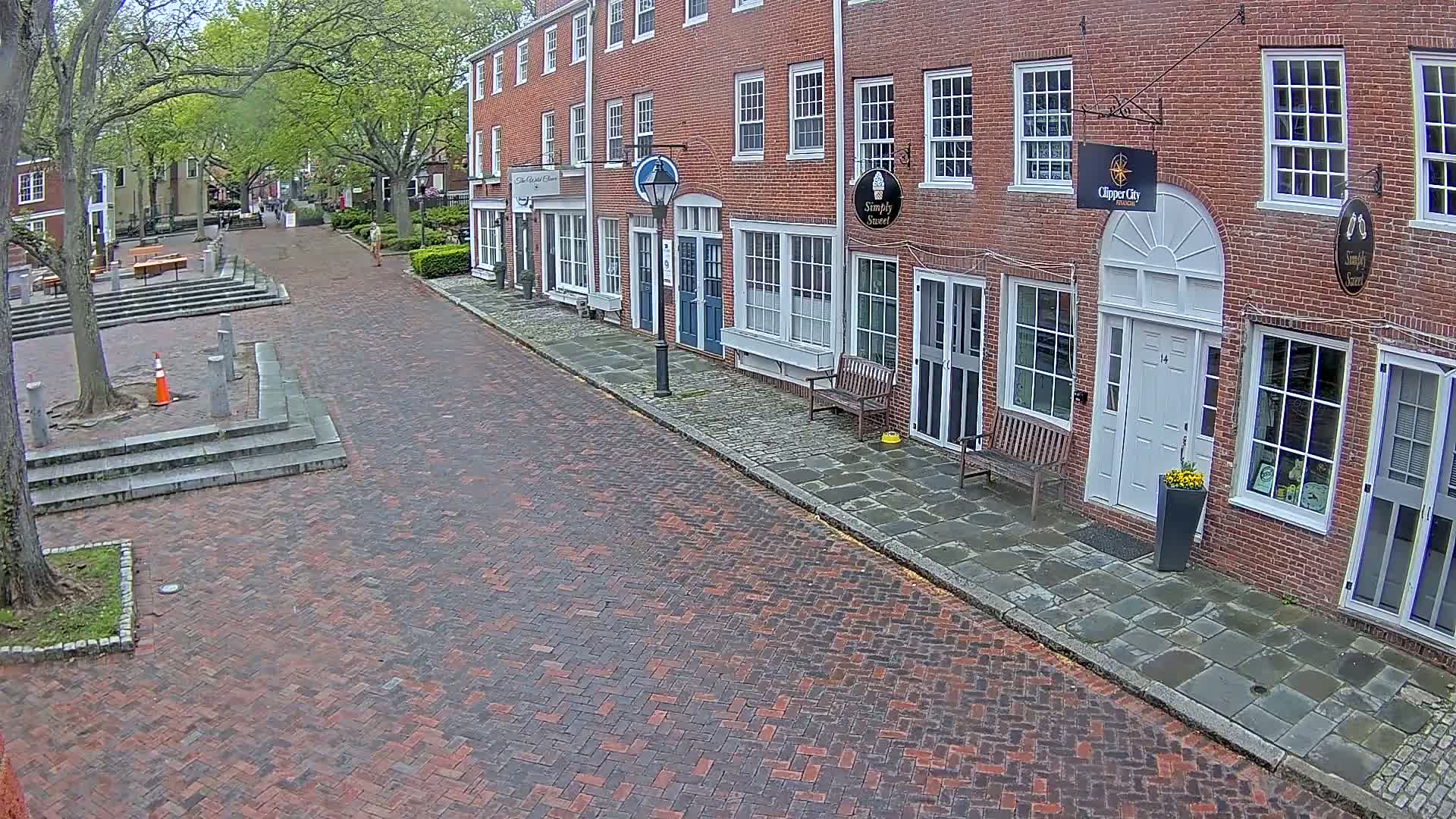A brick street lined with brick buildings under a partly cloudy sky.
