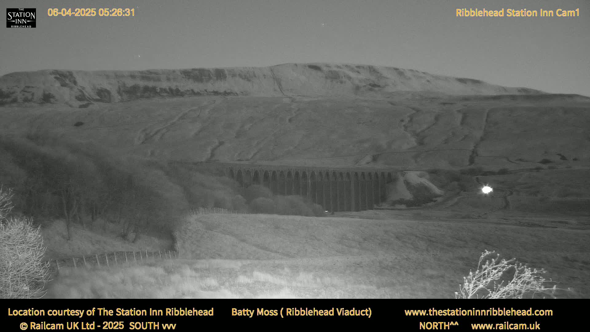 A large stone viaduct is visible beneath a dark hill under a twilight sky.