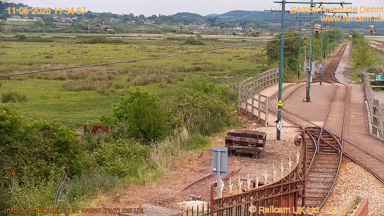 A view of train tracks and a grassy field under an overcast sky.