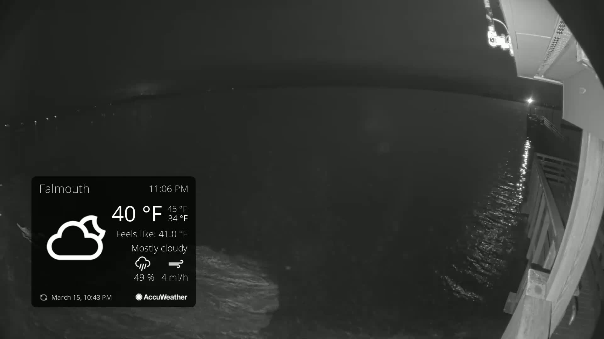 A nighttime view from a pier shows mostly cloudy skies, calm water reflecting light, and a 40°F temperature.