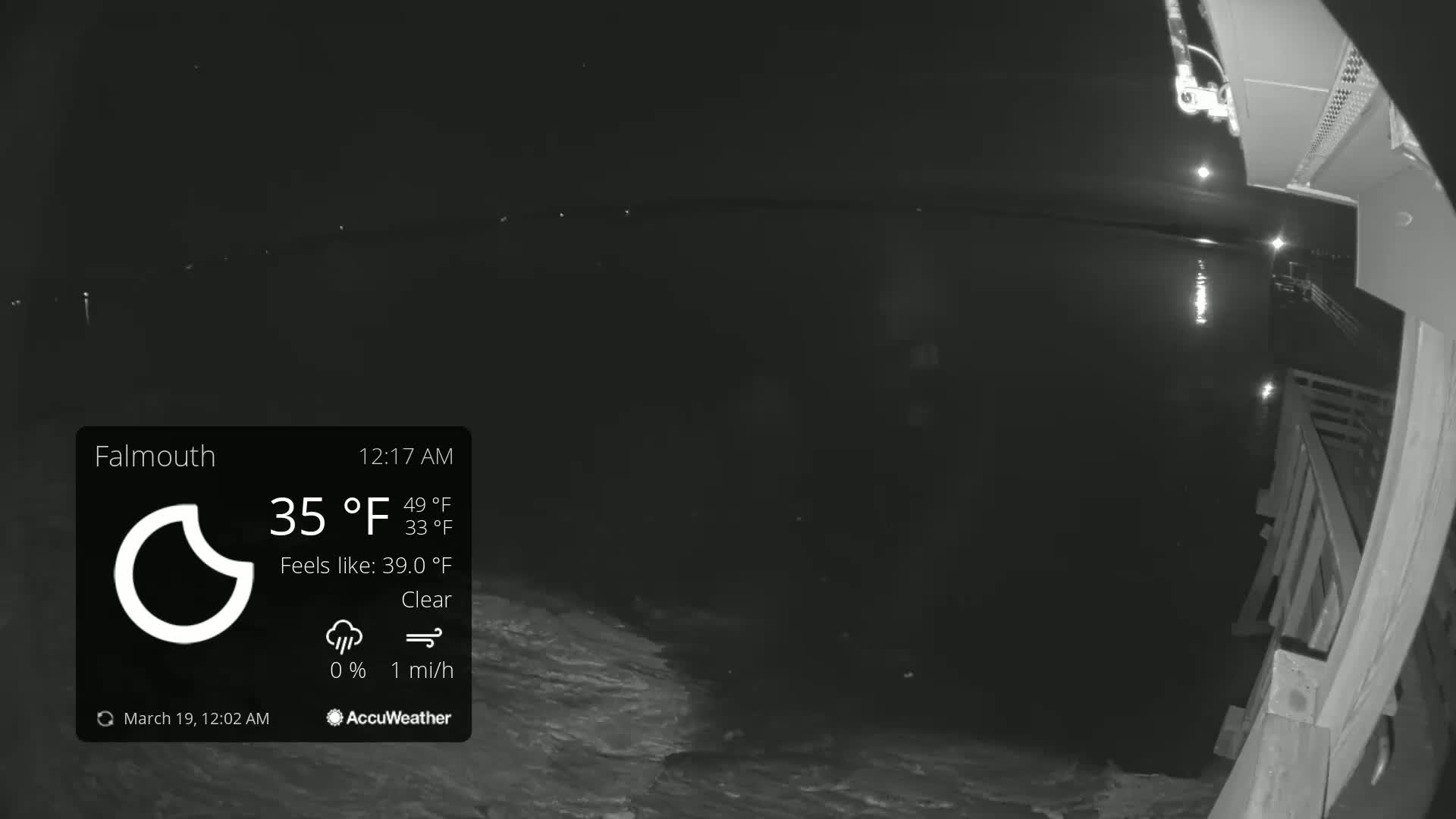 A nighttime, clear view of a dark body of water from a wooden pier under a 35°F sky.