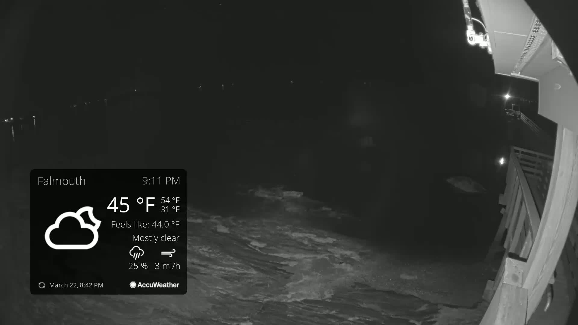 A nighttime, mostly clear view of a dark body of water from a partially visible wooden deck, under a 45°F temperature with a 3 mph wind.