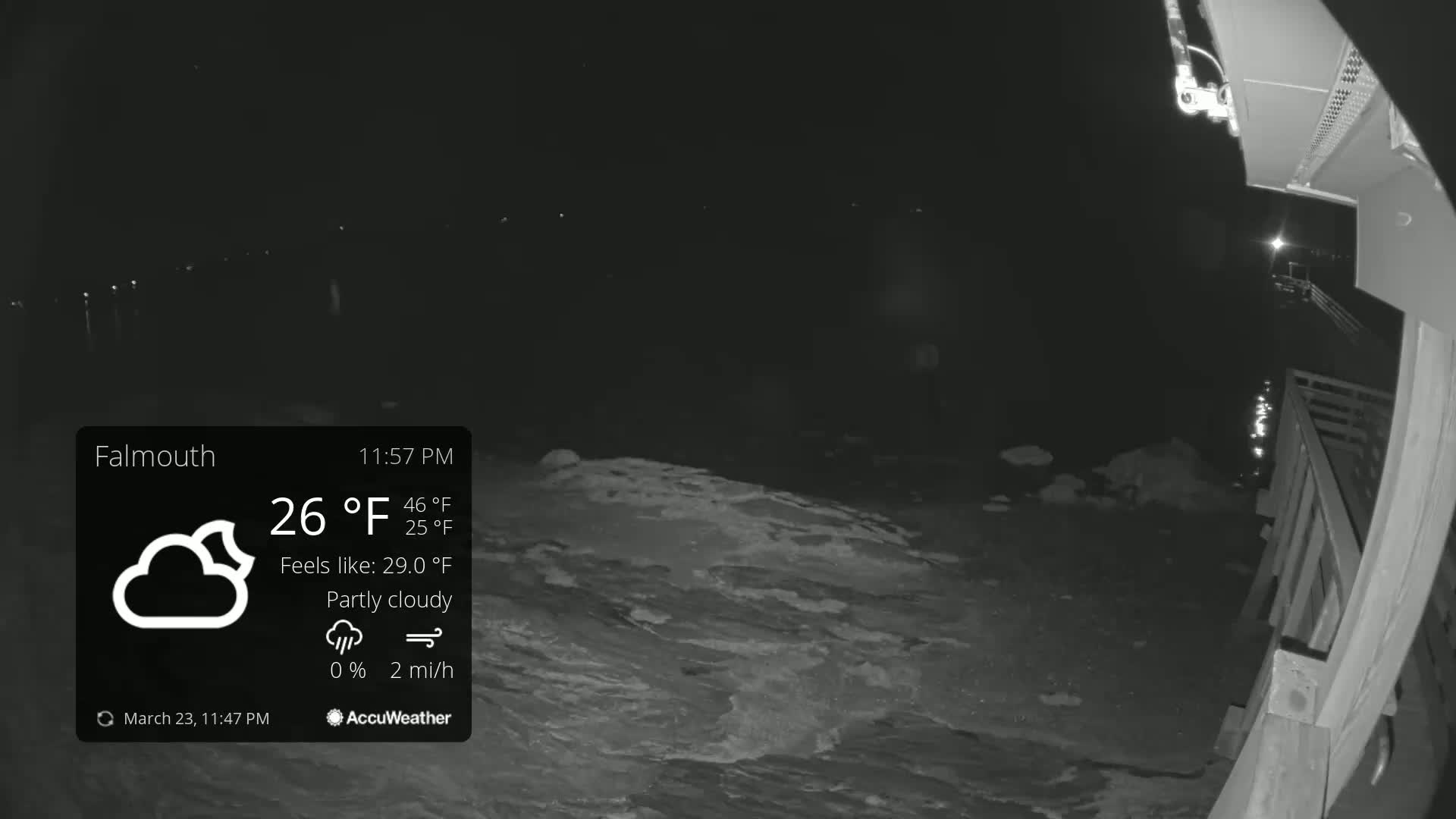 A nighttime, partly cloudy scene shows a dark body of water lapping against a wooden structure, with a 26°F temperature and a 2 mph wind.