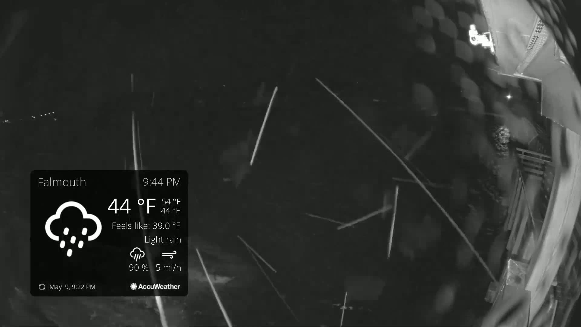 A nighttime, fisheye-lens view shows light rain falling under dark, overcast skies.