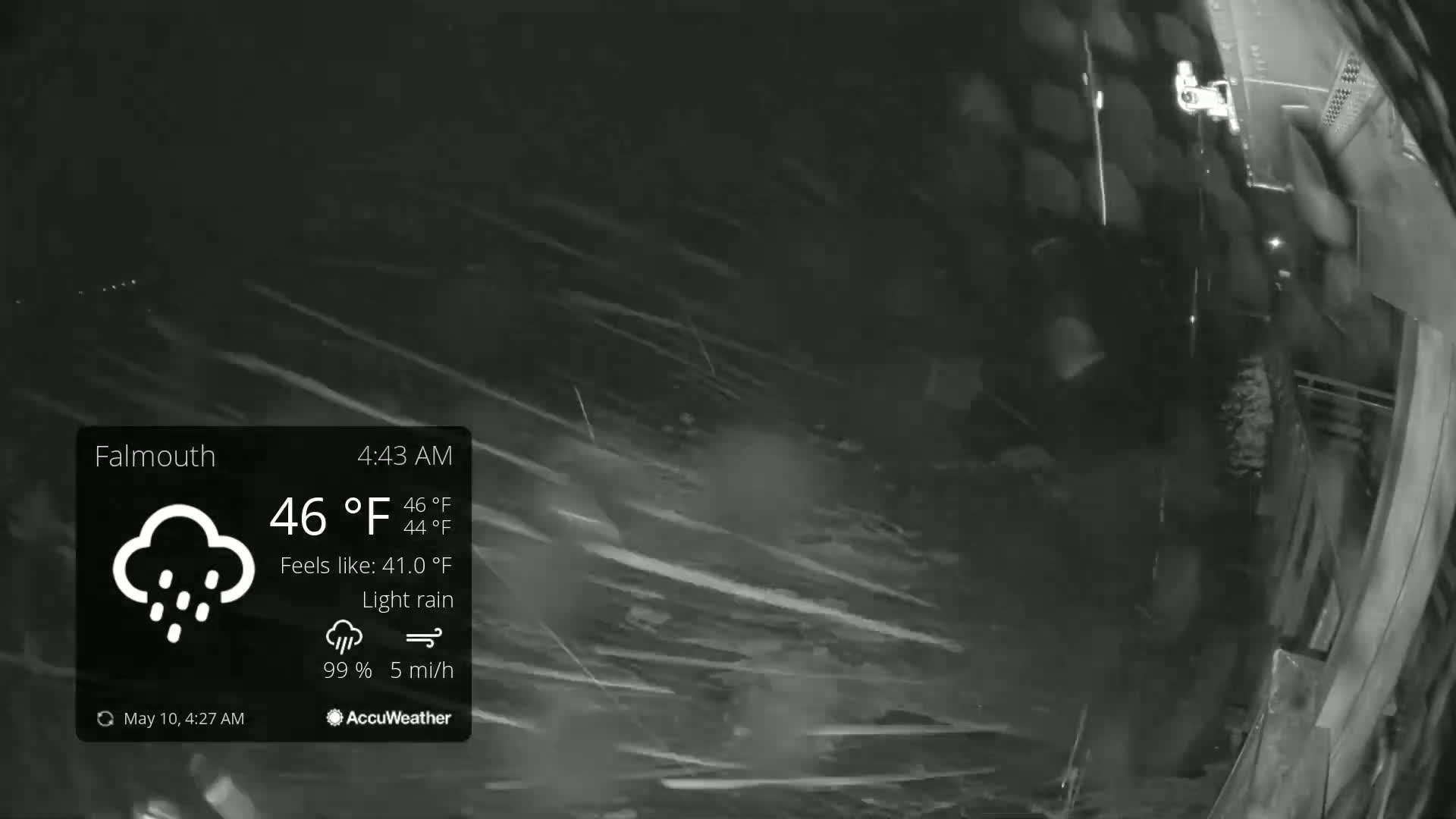 A nighttime, outdoor scene shows light rain falling with a low wind speed.