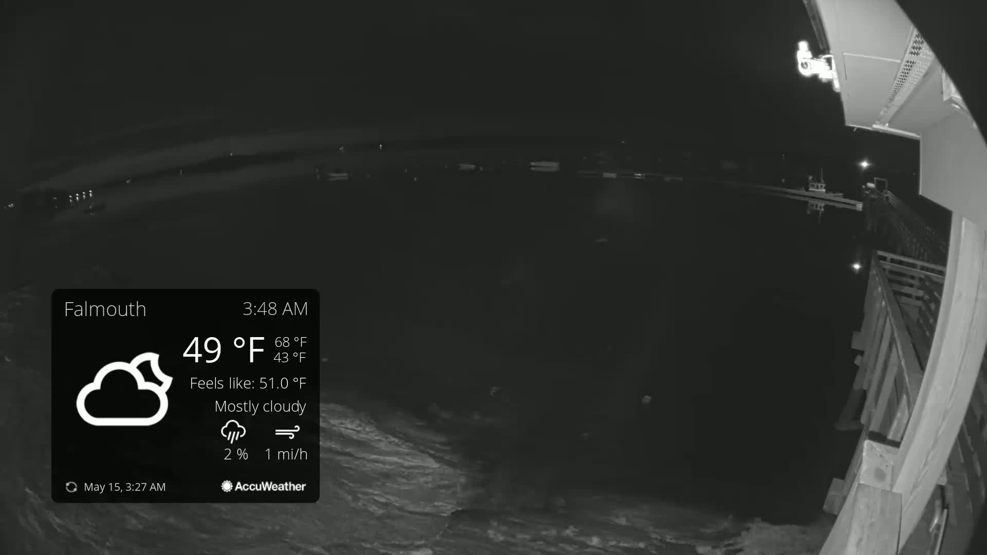 A nighttime, mostly cloudy scene shows dark water with a partially visible pier and a security camera.