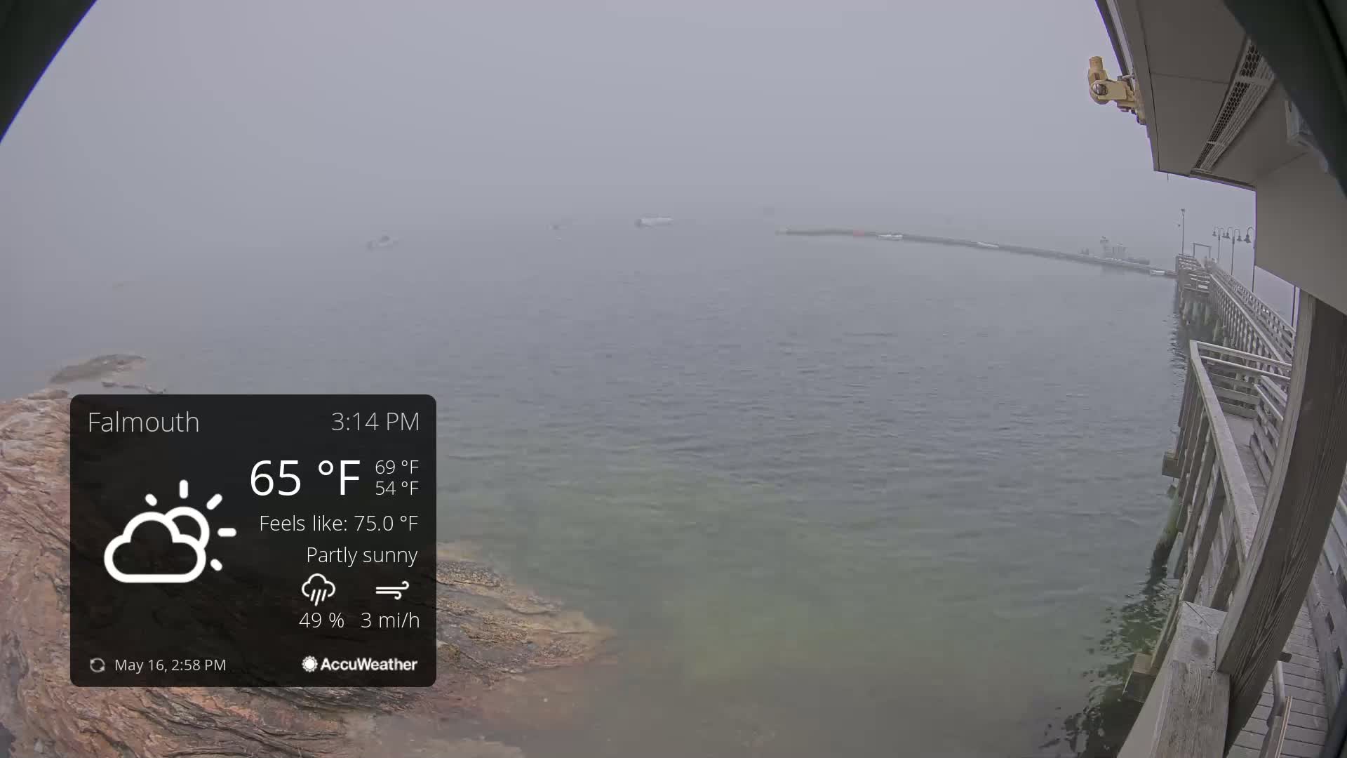 A partly sunny, foggy scene shows a body of water with a wooden pier extending from the bottom right corner into the distance.