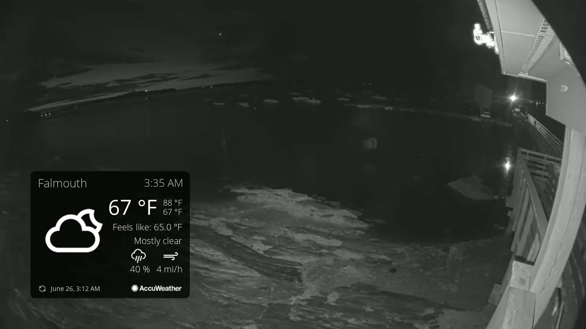 A nighttime, mostly clear view of a body of water from a deck, with a slight breeze.
