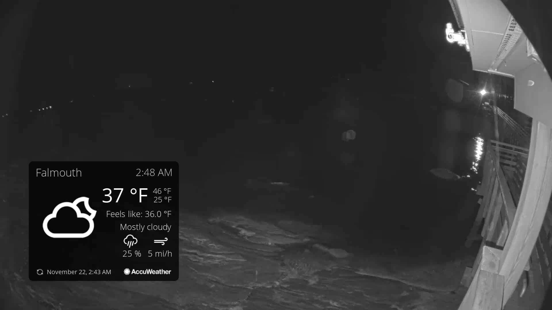 The image shows a dark outdoor scene at night from a structure with wooden railings overlooking choppy water reflecting bright lights, under mostly cloudy skies with a temperature of 37°F.