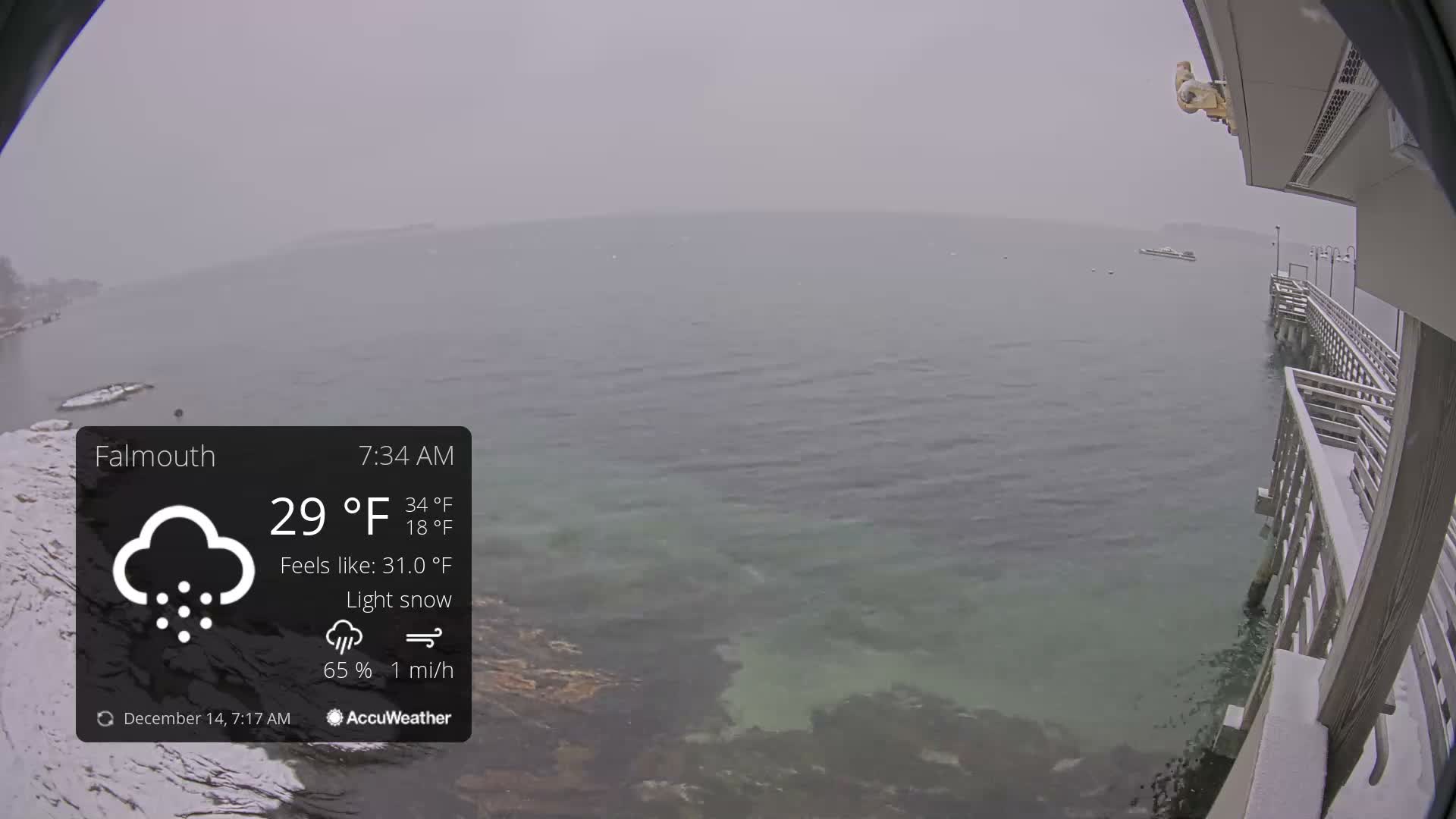The image displays a dark, outdoor night scene of a body of water partially covered in ice or slush, with distant lights on a shoreline and a wooden structure visible on the right, under clear and cold conditions.