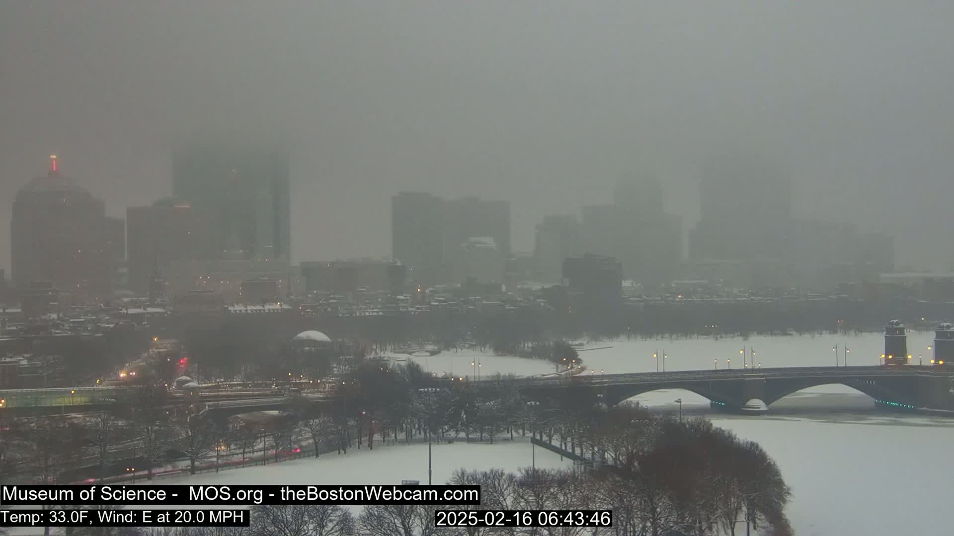A snow-covered city skyline is partially obscured by heavy fog and snow during a blizzard with an easterly wind.
