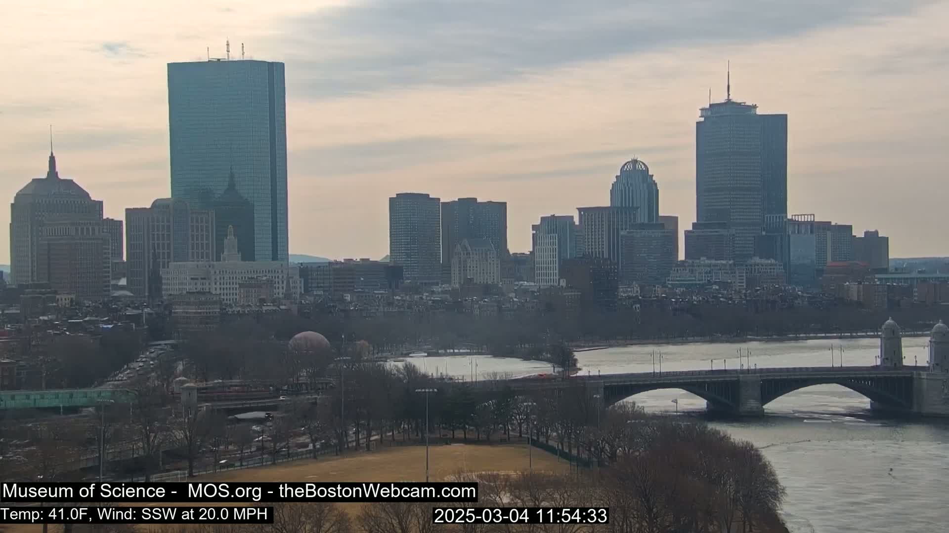 A cityscape with several skyscrapers is visible across a river, under a cloudy sky with a moderate south-southwesterly wind and a temperature of 41 degrees Fahrenheit.