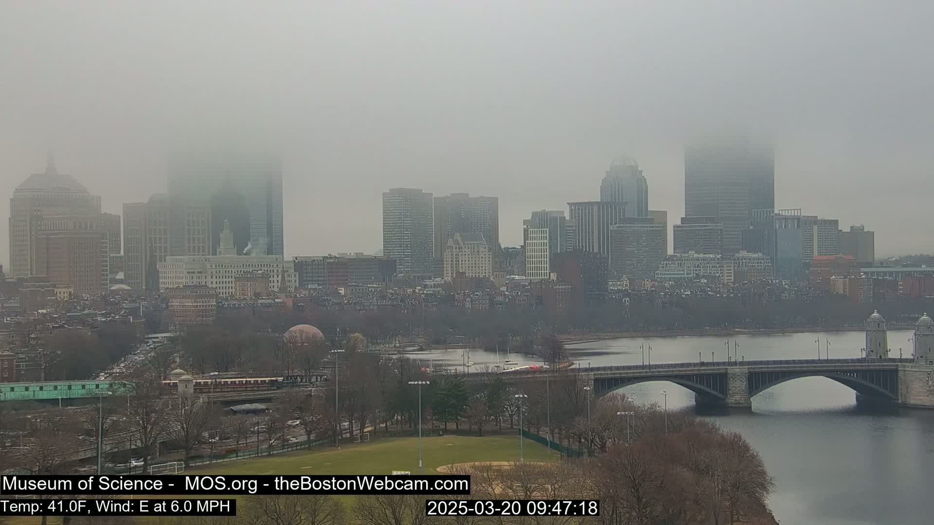 A foggy cityscape with a river and bridge is visible, with the city's skyline partially obscured by mist.