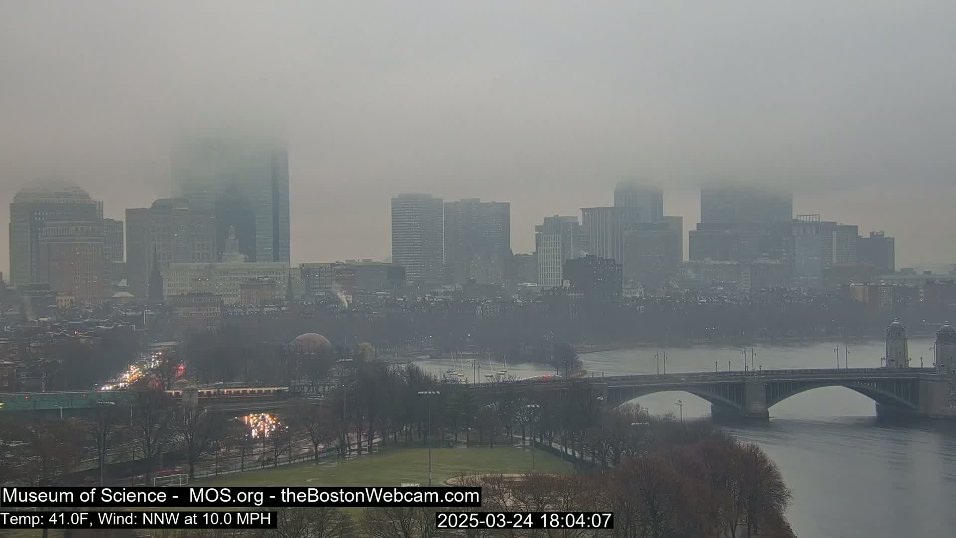 A foggy cityscape with a bridge over a river, viewed from a distance.