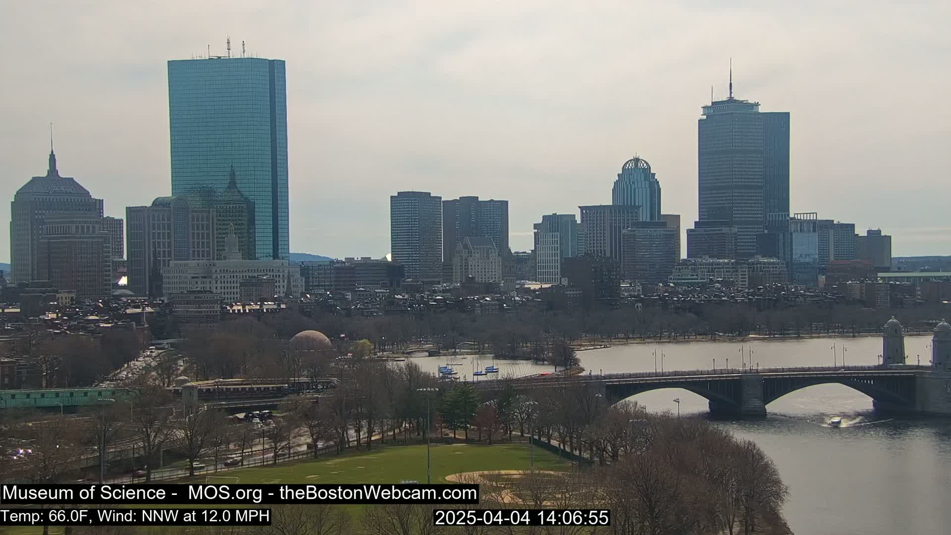 A city skyline with numerous skyscrapers and bridges spans across a river under an overcast sky.