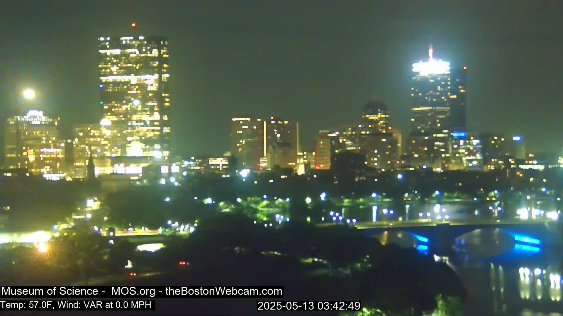 A nighttime view of a city skyline across a body of water, with calm weather conditions.