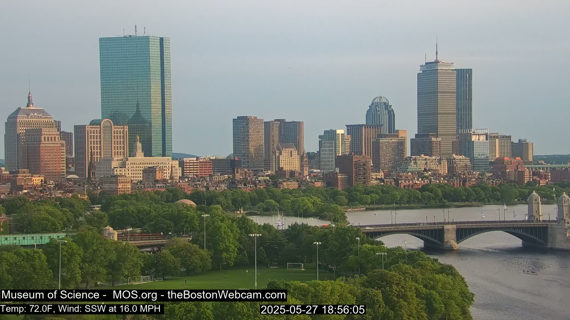 A city skyline with numerous skyscrapers and high-rise buildings is visible across a river with a bridge, under a mostly clear sky.