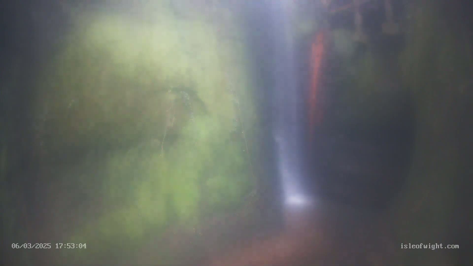 A blurry image shows a waterfall partially obscured by mist and lush green foliage.
