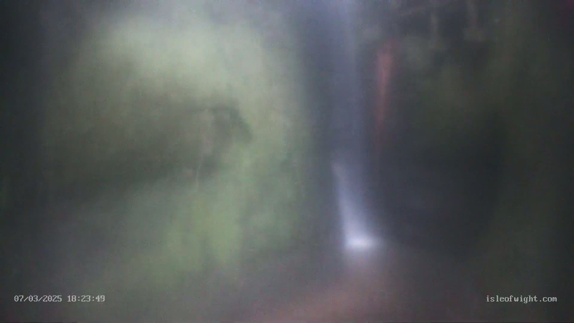 A blurry image shows a waterfall partially obscured by mist in a wooded area.
