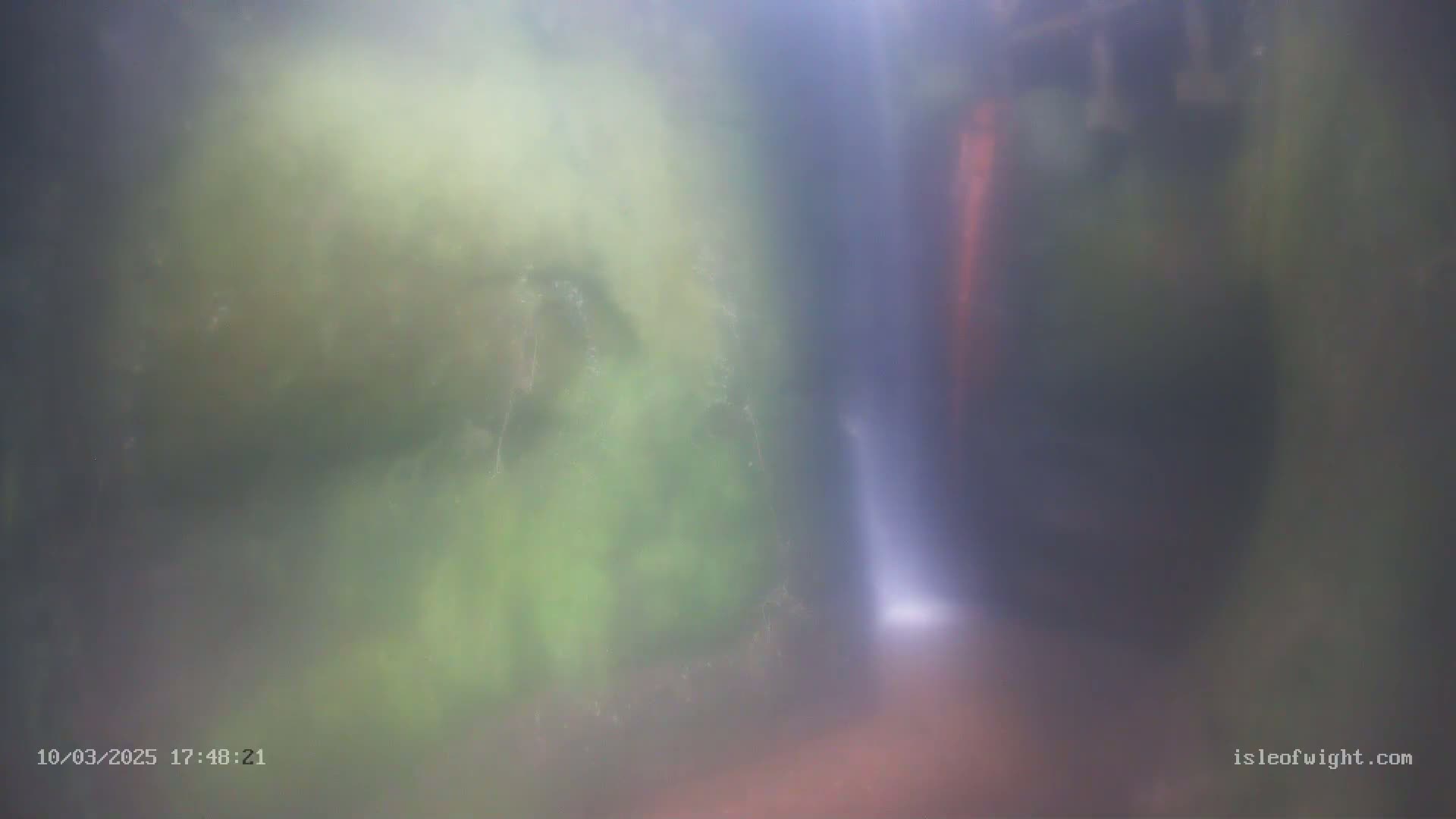 A blurry image shows a waterfall partially obscured by mist and lush green vegetation.