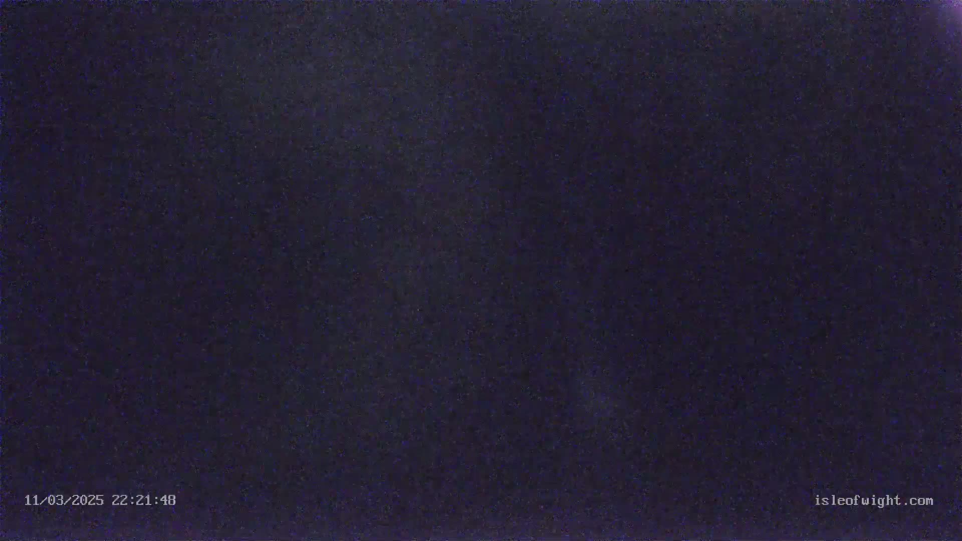 A dark, grainy image shows a night scene with an overcast sky.