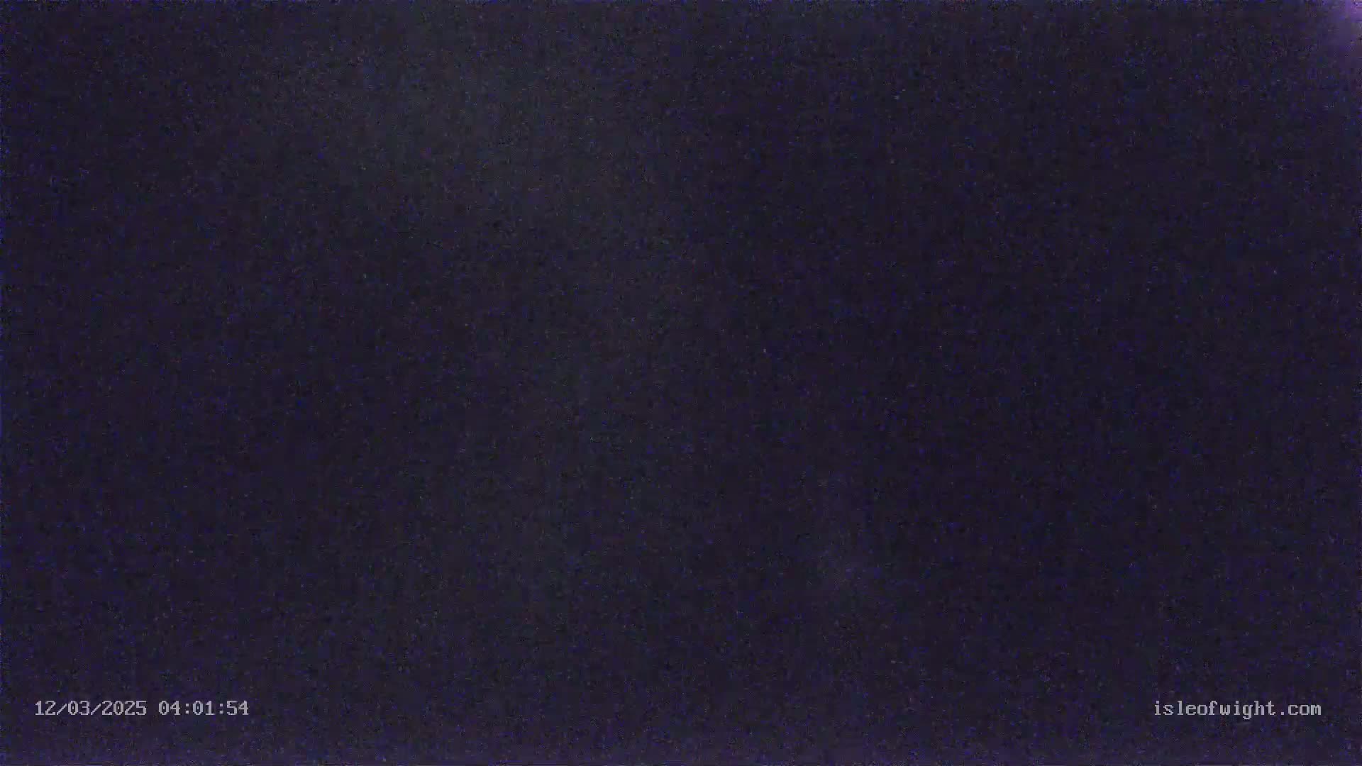 A dark, night-time image shows a mostly clear sky with some faint light speckling.
