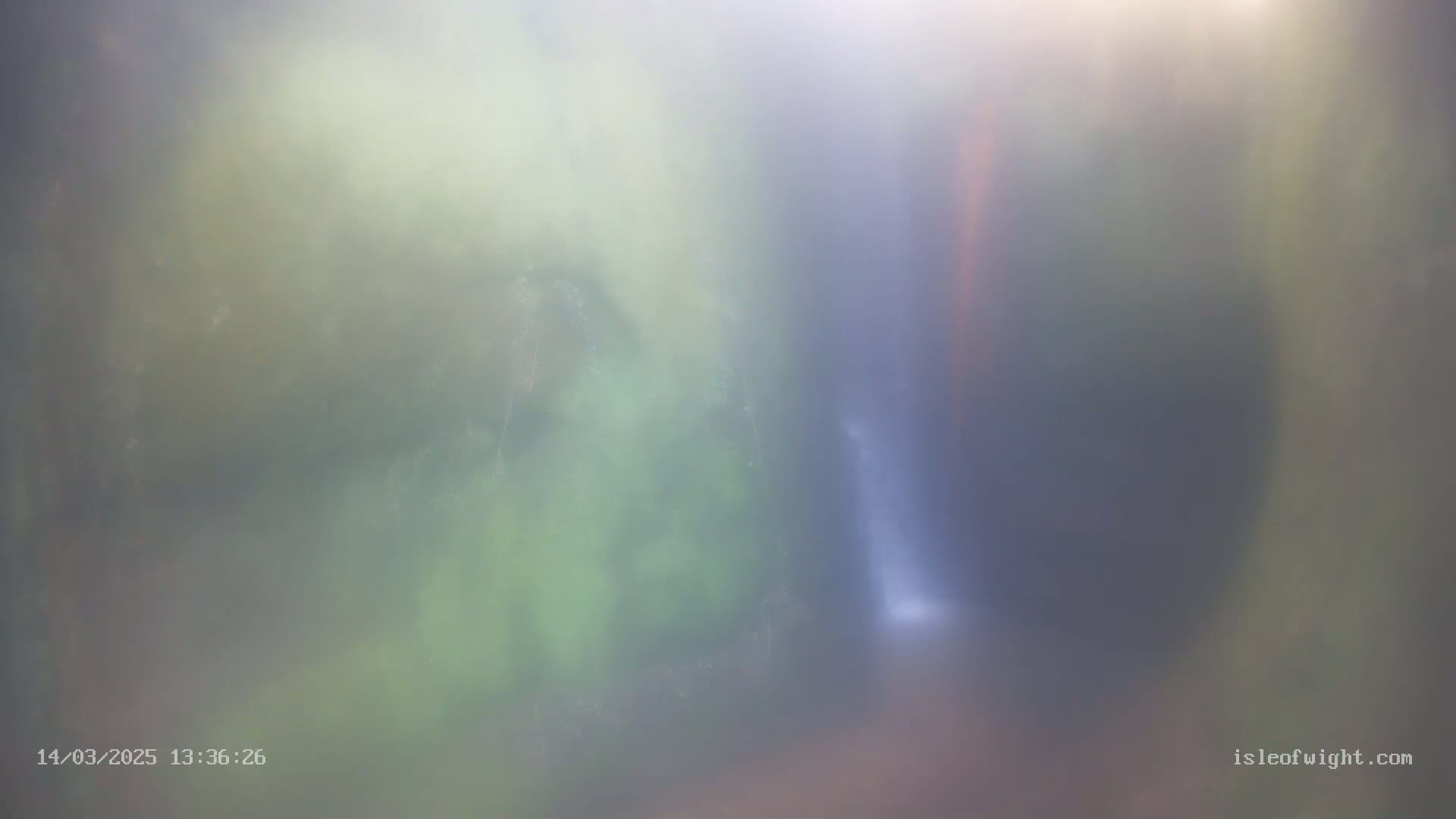 A blurry image shows a misty or foggy scene of what appears to be a waterfall partially obscured by vegetation.