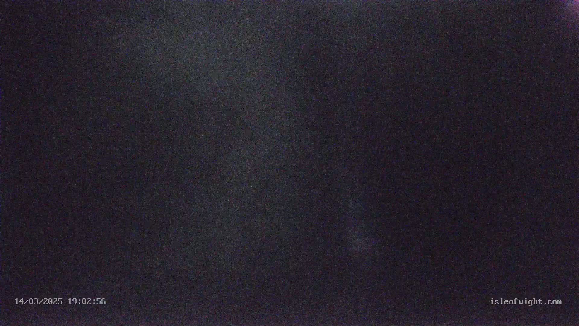 A dark, grainy image shows a night sky with a faint, vertical streak of light.