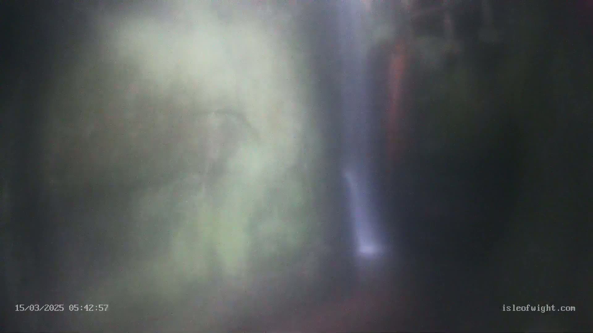 A blurry image shows a thin waterfall cascading down a dark, misty cliff face.