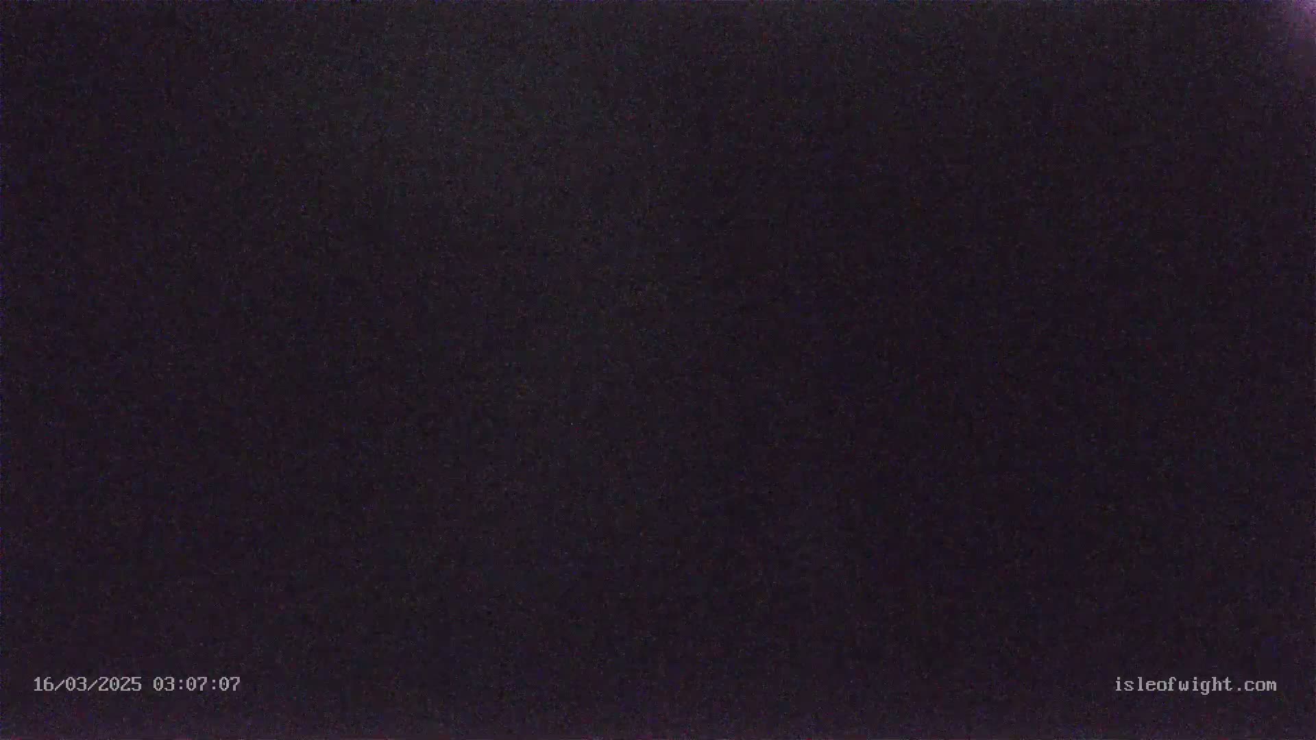 A dark, nighttime image shows a mostly uniform black or dark-purple surface with subtle texture.
