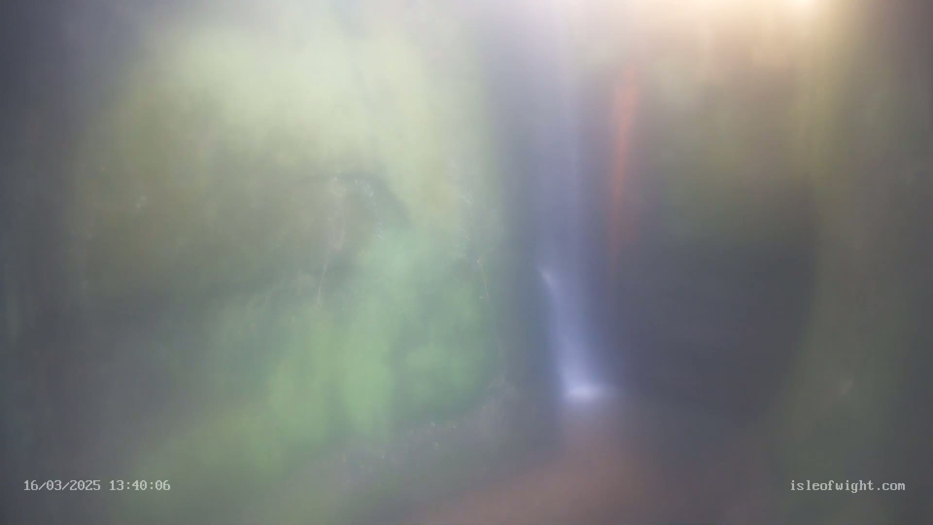 A blurry image shows a waterfall partially obscured by mist in a lush green forest.